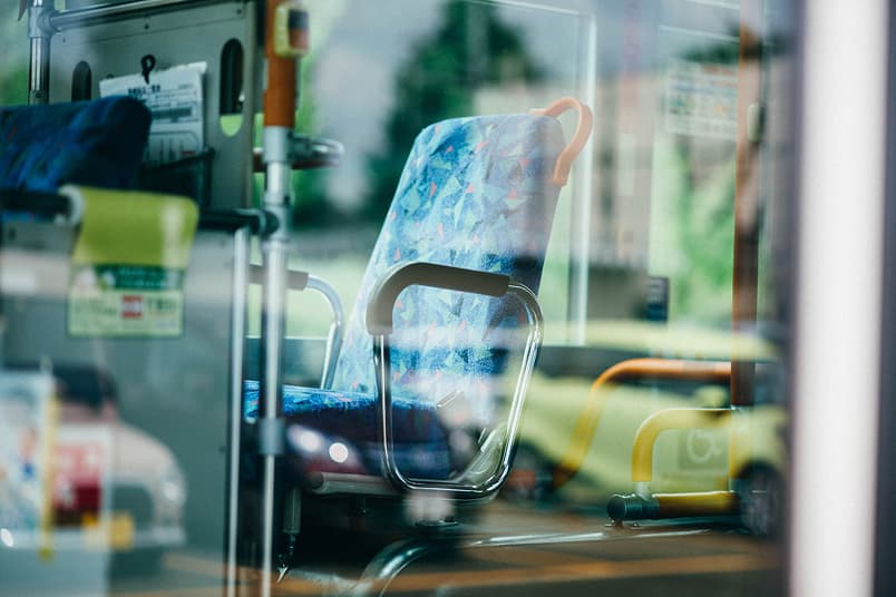 バス車内の青い柄の座席と手すり、窓の外に緑が見える、イメージ